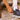 man placing foot into shoe with socks. Dirt trail in background